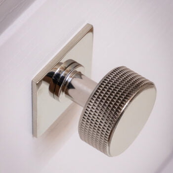 Metal door knob on a white door, textured grip.