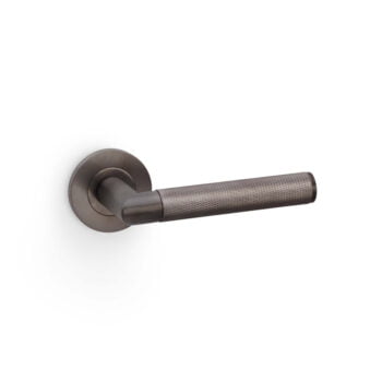 Modern textured bronze door handle on white background.