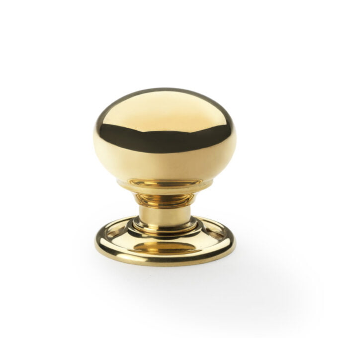 Polished gold cabinet knob on white background.