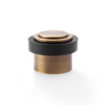 Brass and black flush door stop on white background.