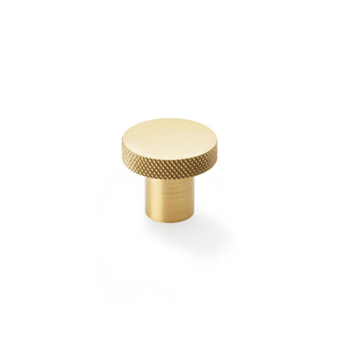 Brass cabinet knob with textured edge on white background