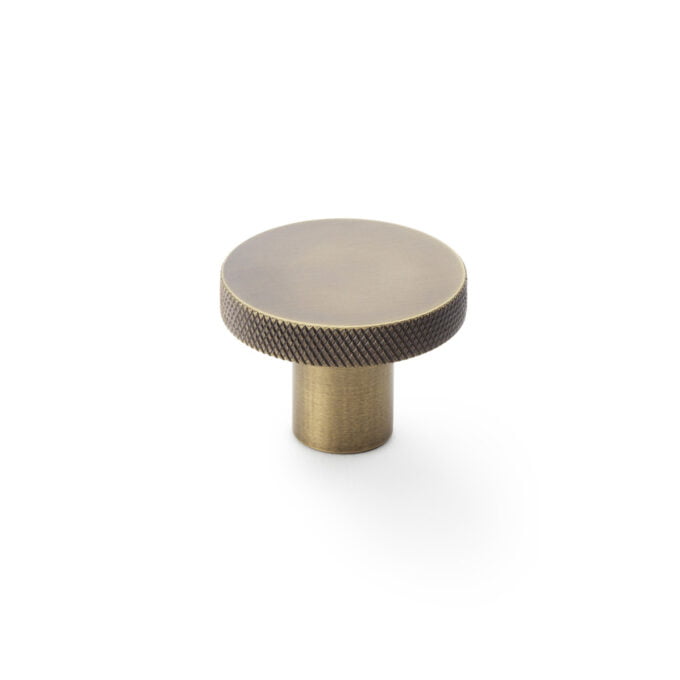 Brass knob with textured edge on white background.