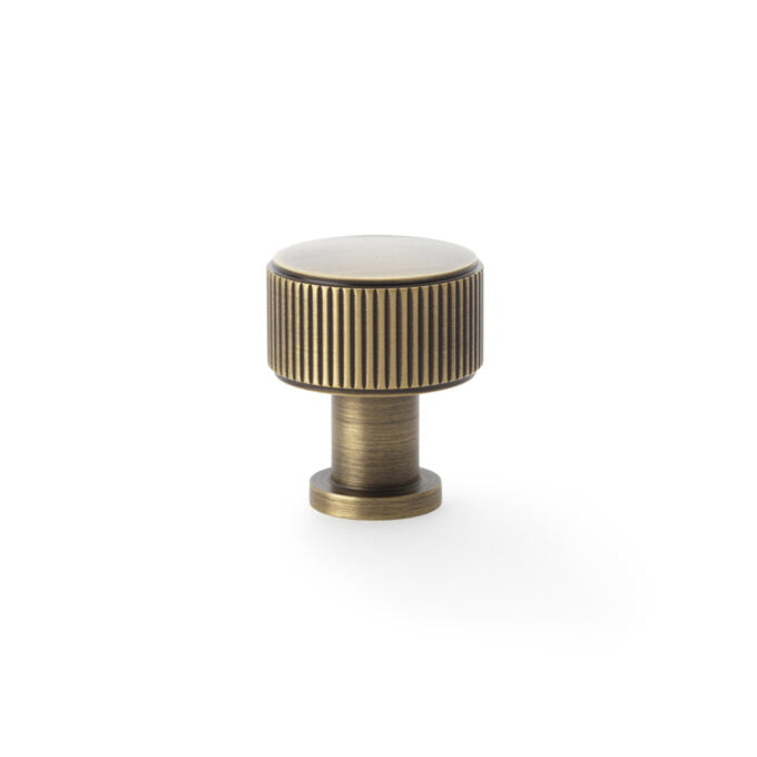 Brass cabinet knob with ridged detail on white background.