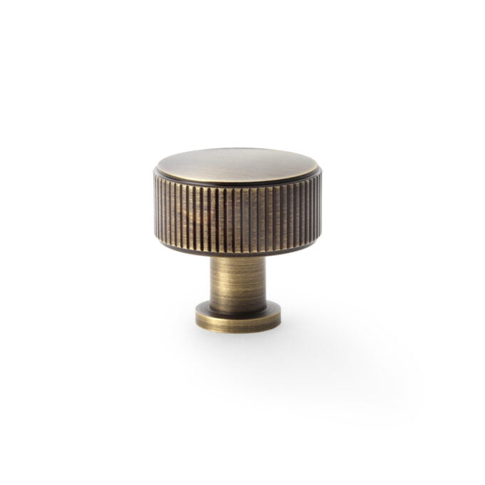 Antique brass cabinet knob on white background.