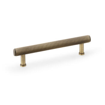 Brass cabinet handle with ridged texture on white background