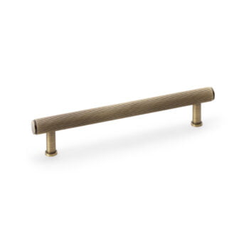 Brass ridged cabinet handle on white background.