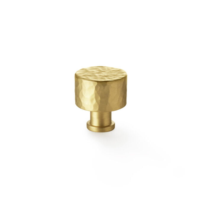 Hammered brass cabinet knob on white background