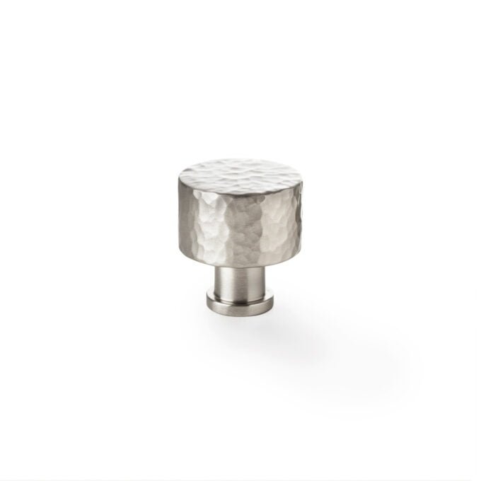 Hammered metal cabinet knob on white background.