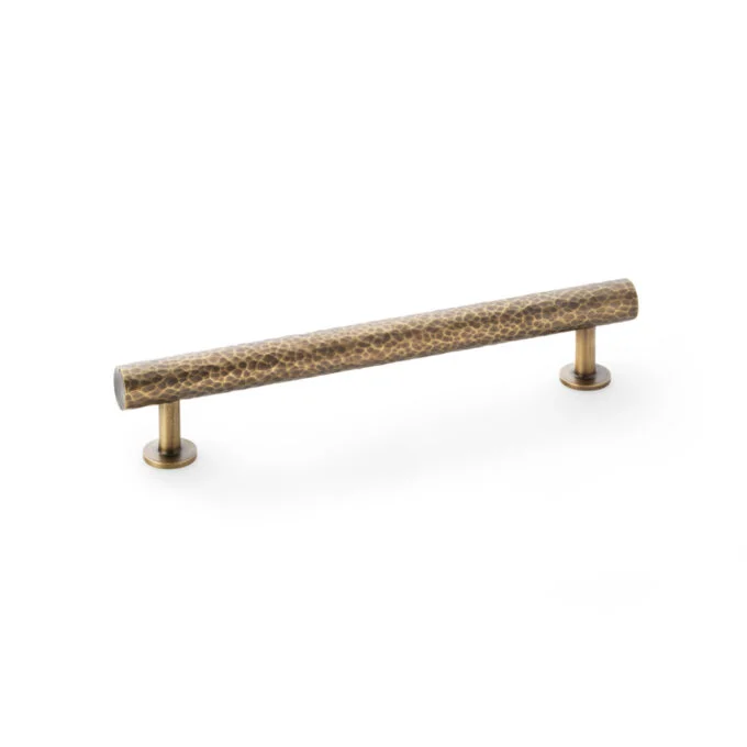 Textured brass cabinet handle on white background.