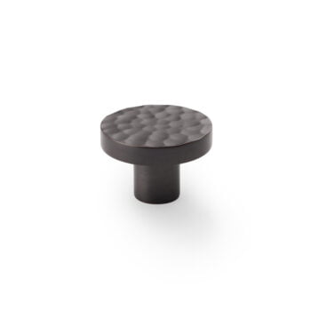 Textured black cabinet knob isolated on white.