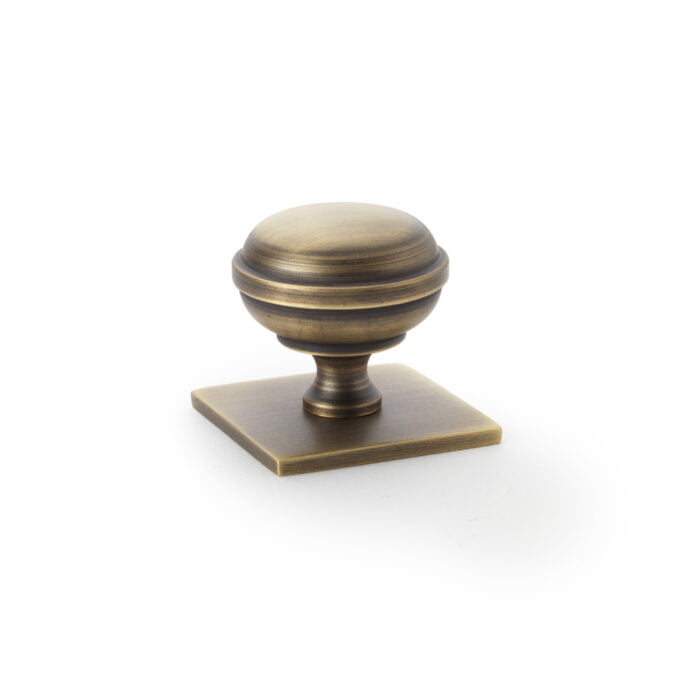 Antique brass cabinet knob on white background.