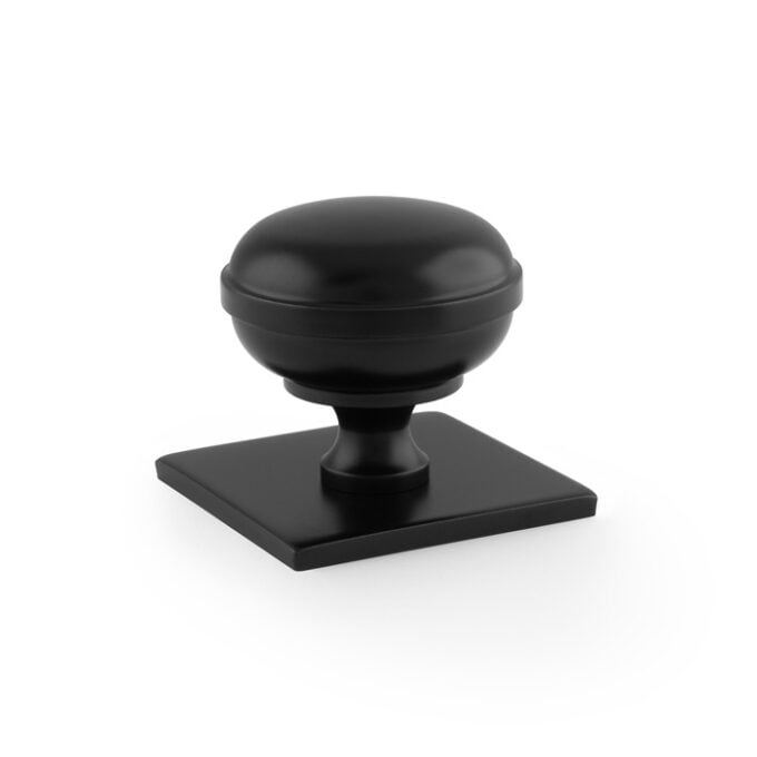 Black cabinet knob on white background.