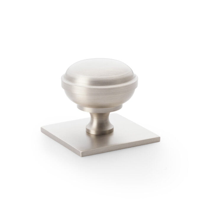 Brushed nickel cabinet knob on white background.