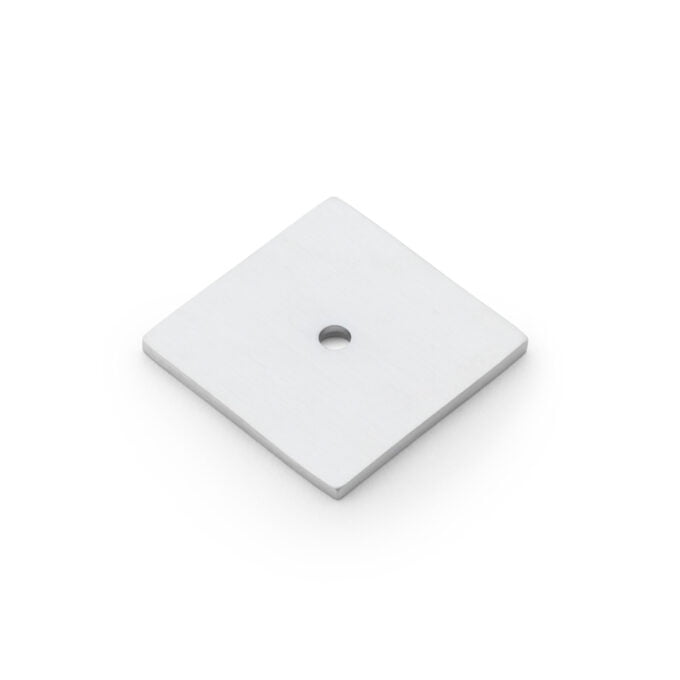 Square metal plate with central hole on white background.