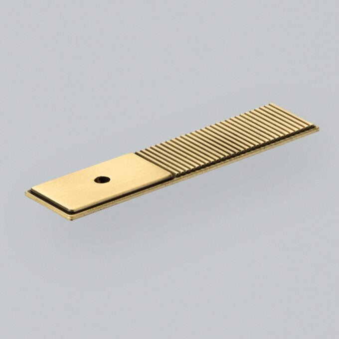 Brass metal comb with fine teeth on grey background.