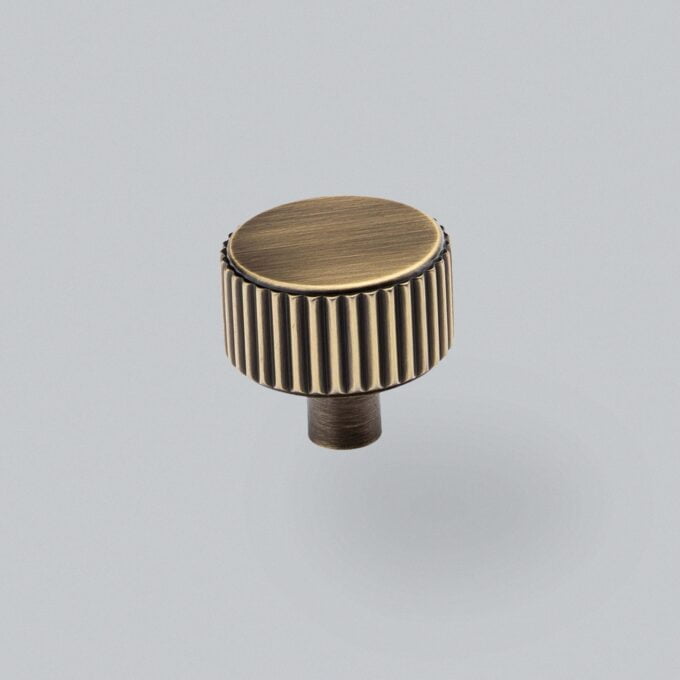 Antique brass cabinet knob against a grey background.