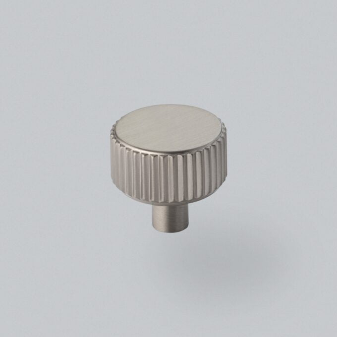 Metal knob with ridged edge on grey background.