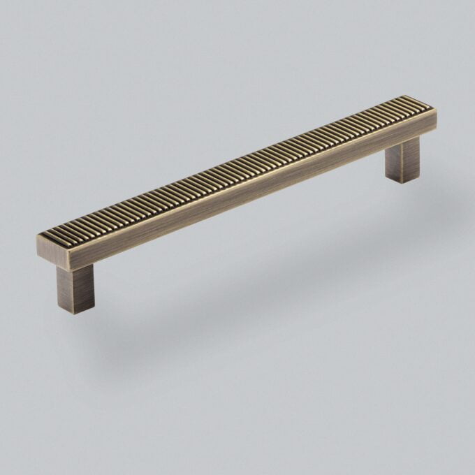 Metal cabinet handle with textured design on grey background.