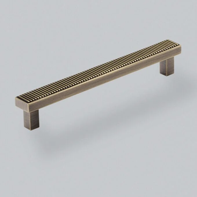 Metal cabinet handle with textured design on grey background.