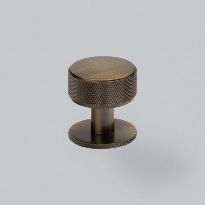 Bronze textured cabinet doorknob on grey background.