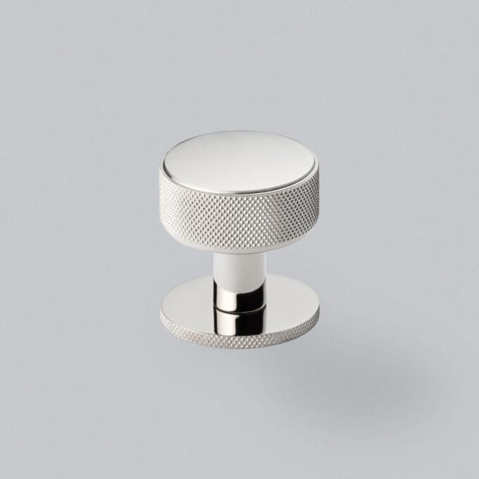 Chrome knob with textured grip on grey background