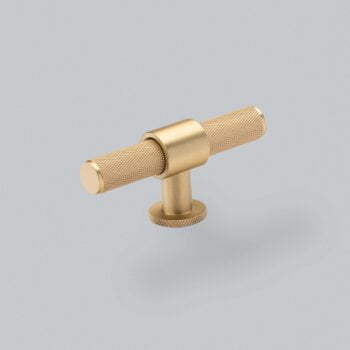 Brass cabinet handle on grey background.