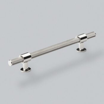 Knurled chrome metal cabinet handle on grey background.