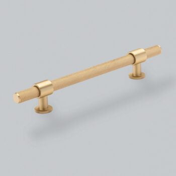 Gold knurled cabinet handle on grey background.