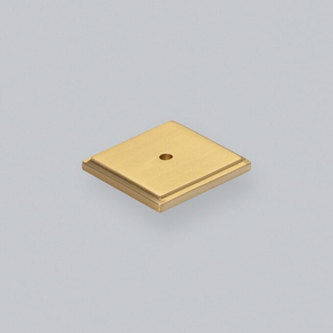 Gold square block with central hole on grey background.