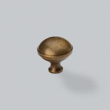 Antique bronze cabinet knob on a grey background.