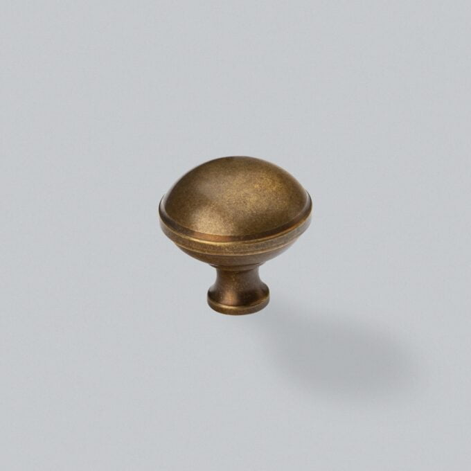 Antique bronze cabinet knob on a grey background.