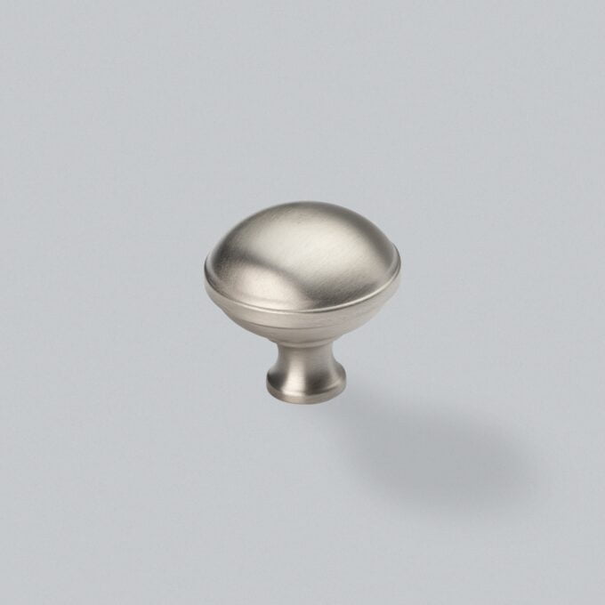 Brushed nickel cabinet knob on grey background.