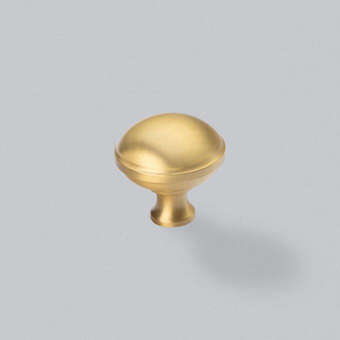 Gold cabinet knob on grey background.