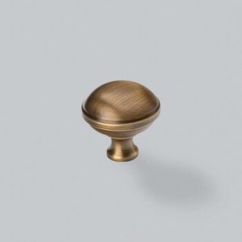 Antique brass cabinet knob on grey background.