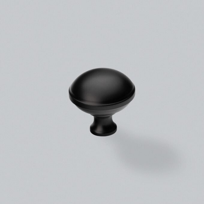 Black cabinet knob on grey background.