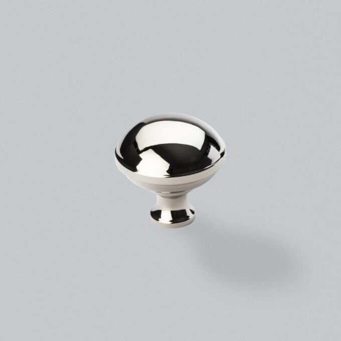 Shiny chrome cabinet knob on grey background.