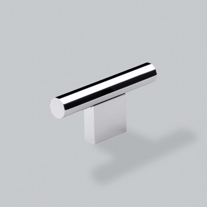 Chrome cylinder on white block, minimalist design.