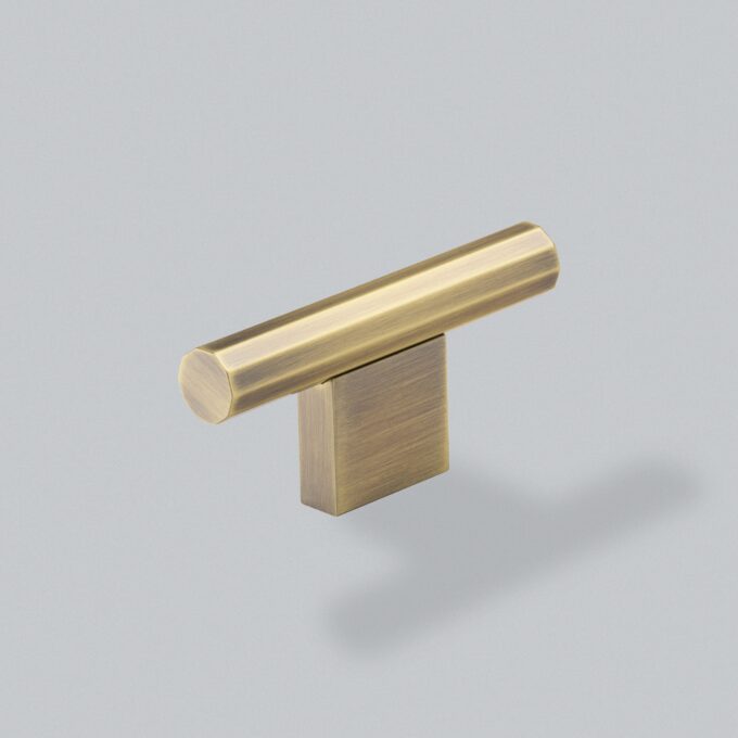 Brass T-bar cabinet handle on grey background