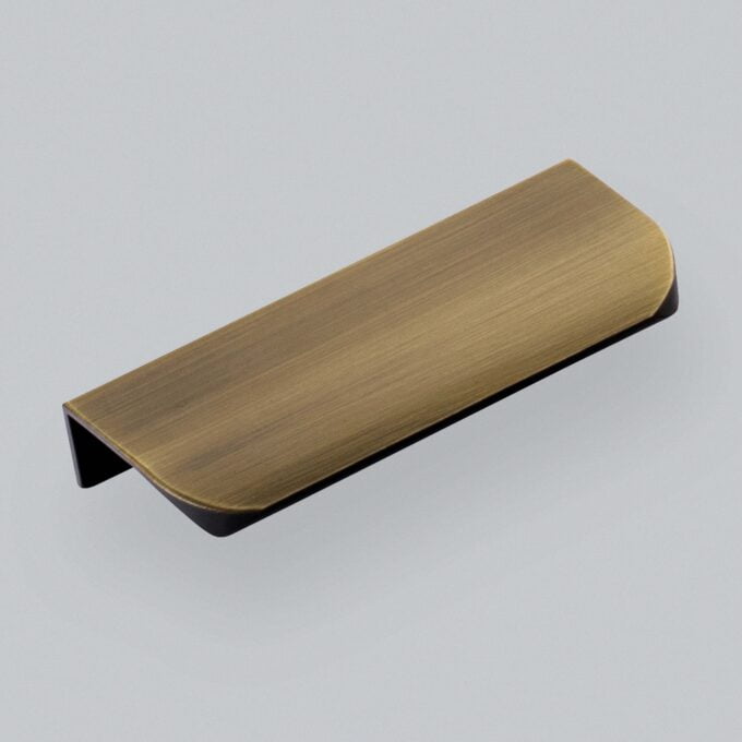 Brushed gold cabinet handle on gray background.