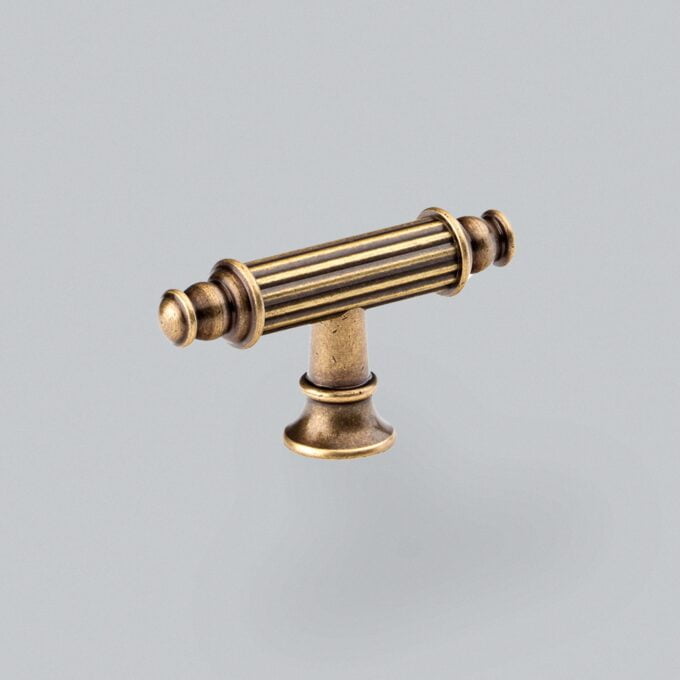 Antique brass drawer handle on grey background.