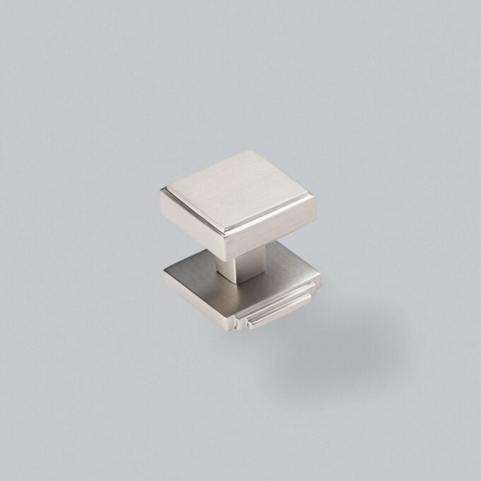 Square silver cabinet knob on grey background.