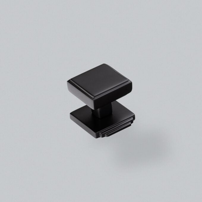 Black modern cabinet knob on a grey background.