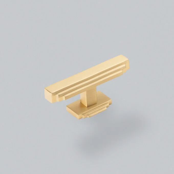 Gold cabinet handle on grey background.