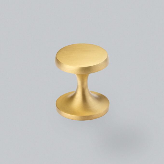 Brushed gold metal door knob on grey background.