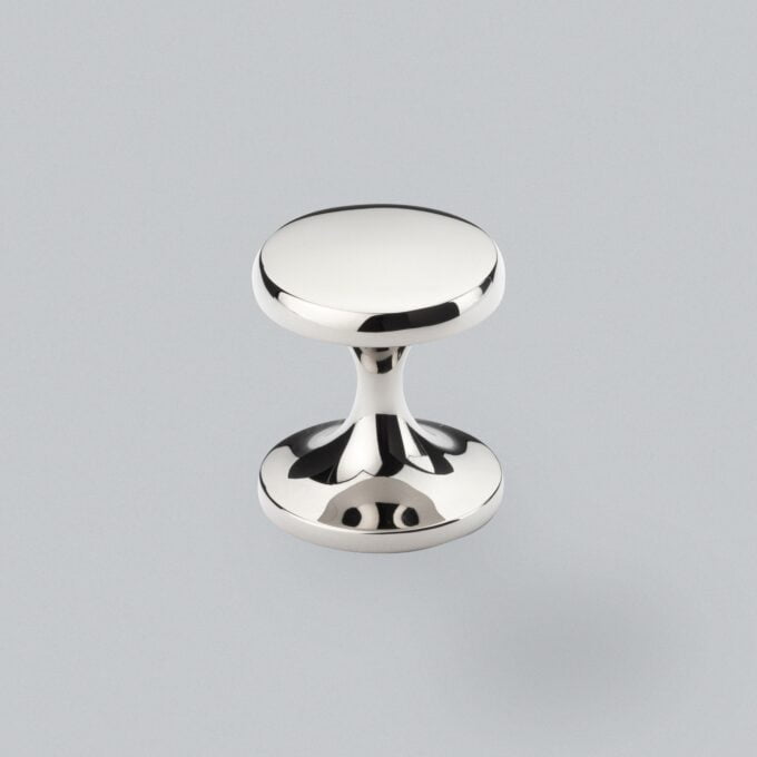 Shiny chrome dumbbell-shaped paperweight on grey background.