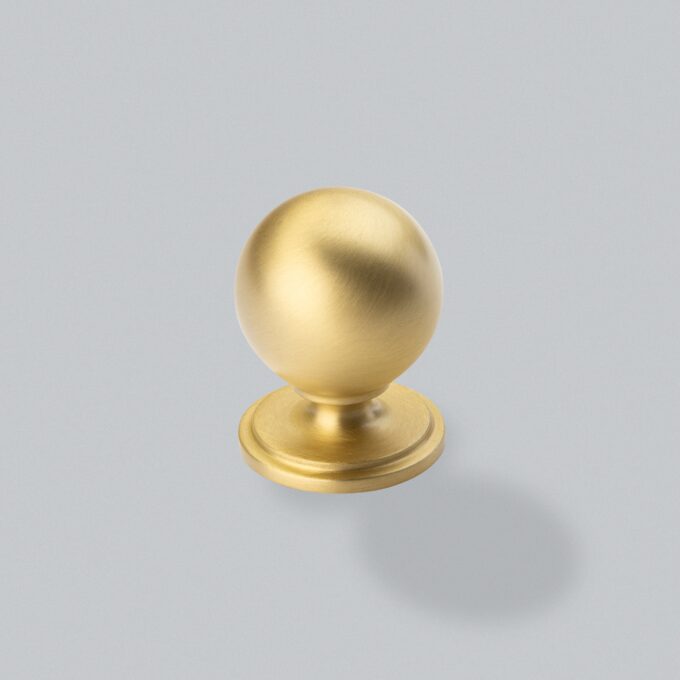 Gold spherical cabinet knob on grey background.