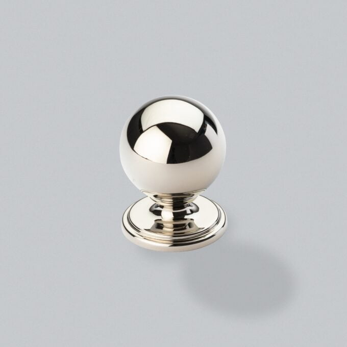 Polished chrome spherical door knob on grey background.