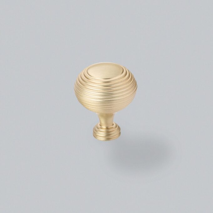 Brass spherical door knob on grey background.