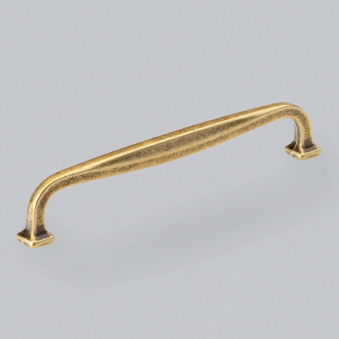 Antique brass cabinet handle on grey background.