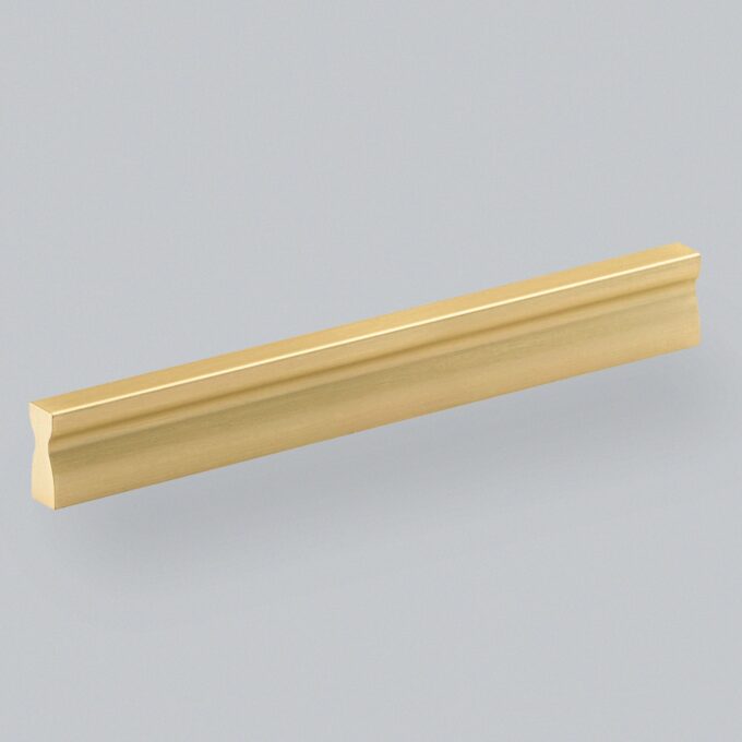 Gold-coloured cabinet handle on grey background.